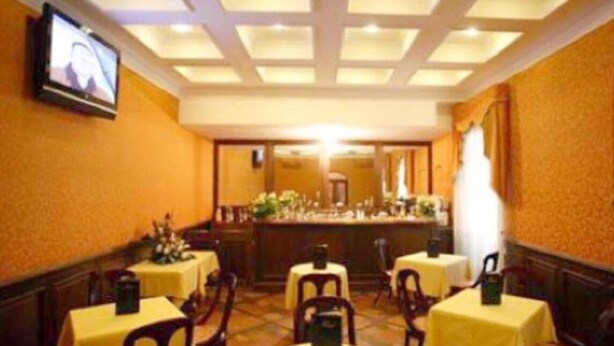 A hotel dining area with round tables, chairs, and a bar counter. - Hotel Guiren (Naples)