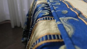 A bed with a blue and gold patterned bedspread. - Hotel Guiren (Naples)