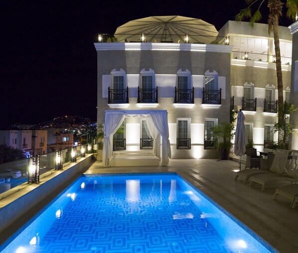 A pool with a geometric pattern, a building with balconies and a covered area, and a palm tree. - Ena Boutique Hotel & Residences (Bodrum)
