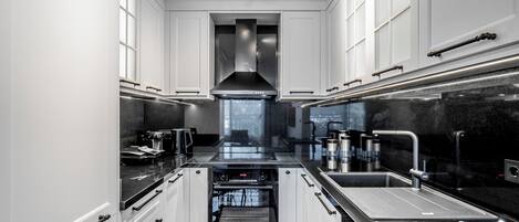 Una cocina moderna con armarios blancos, horno empotrado y encimera negra.
