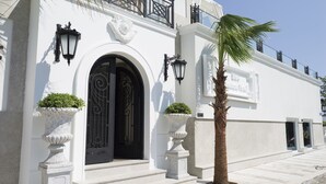 Un edificio blanco con una entrada arqueada grande, dos macetas y una palmera.