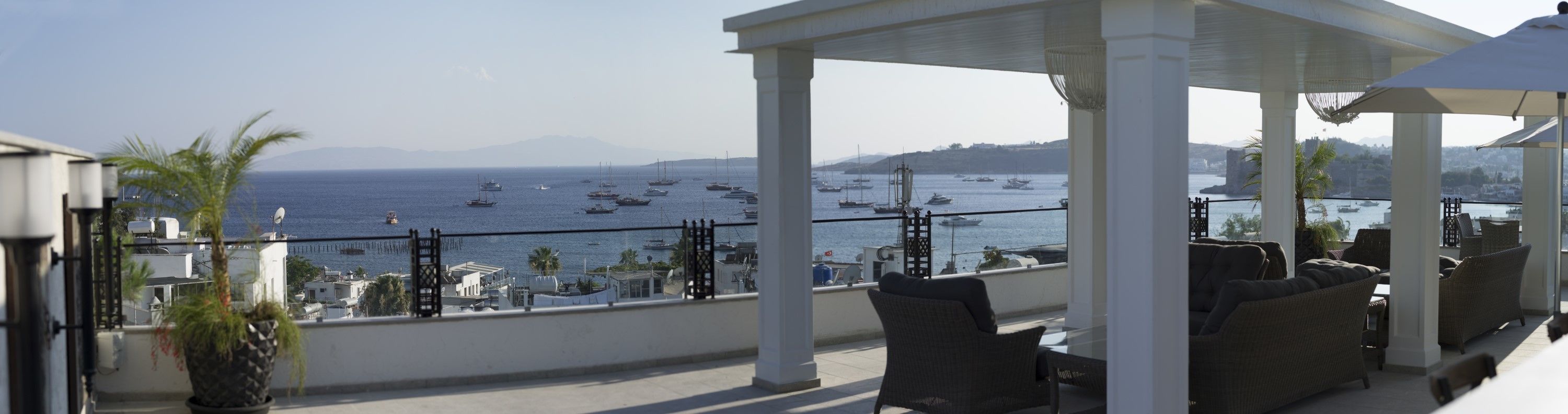 Une terrasse avec des places assises extérieures donnant sur une marina où sont amarrés des bateaux.