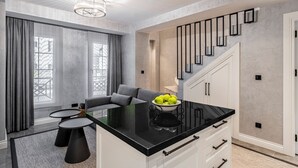 Una cocina moderna con encimera negra, armarios blancos y una escalera con barandillas negras.