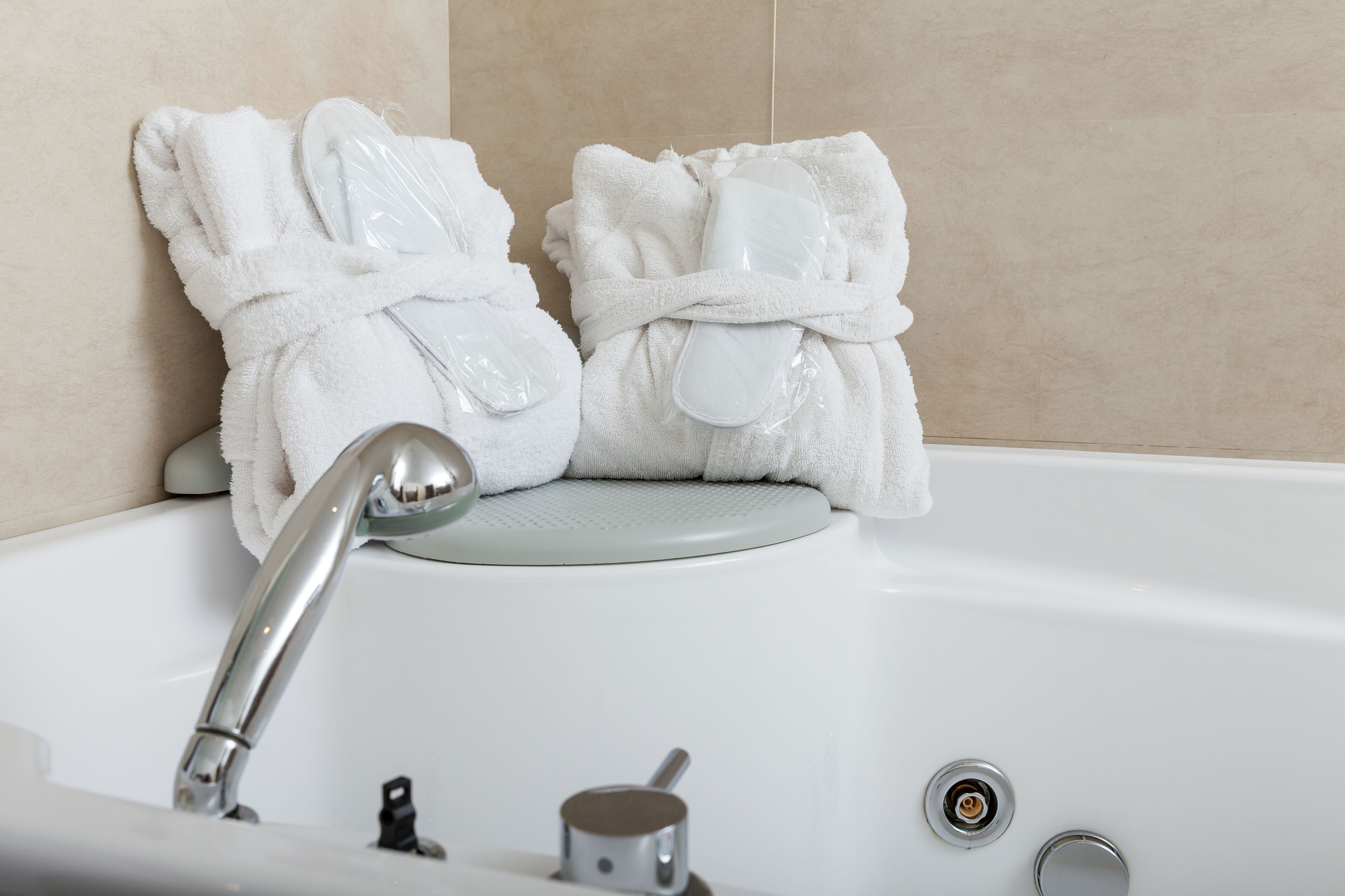 A bathtub with two white towels and a white bottle.
