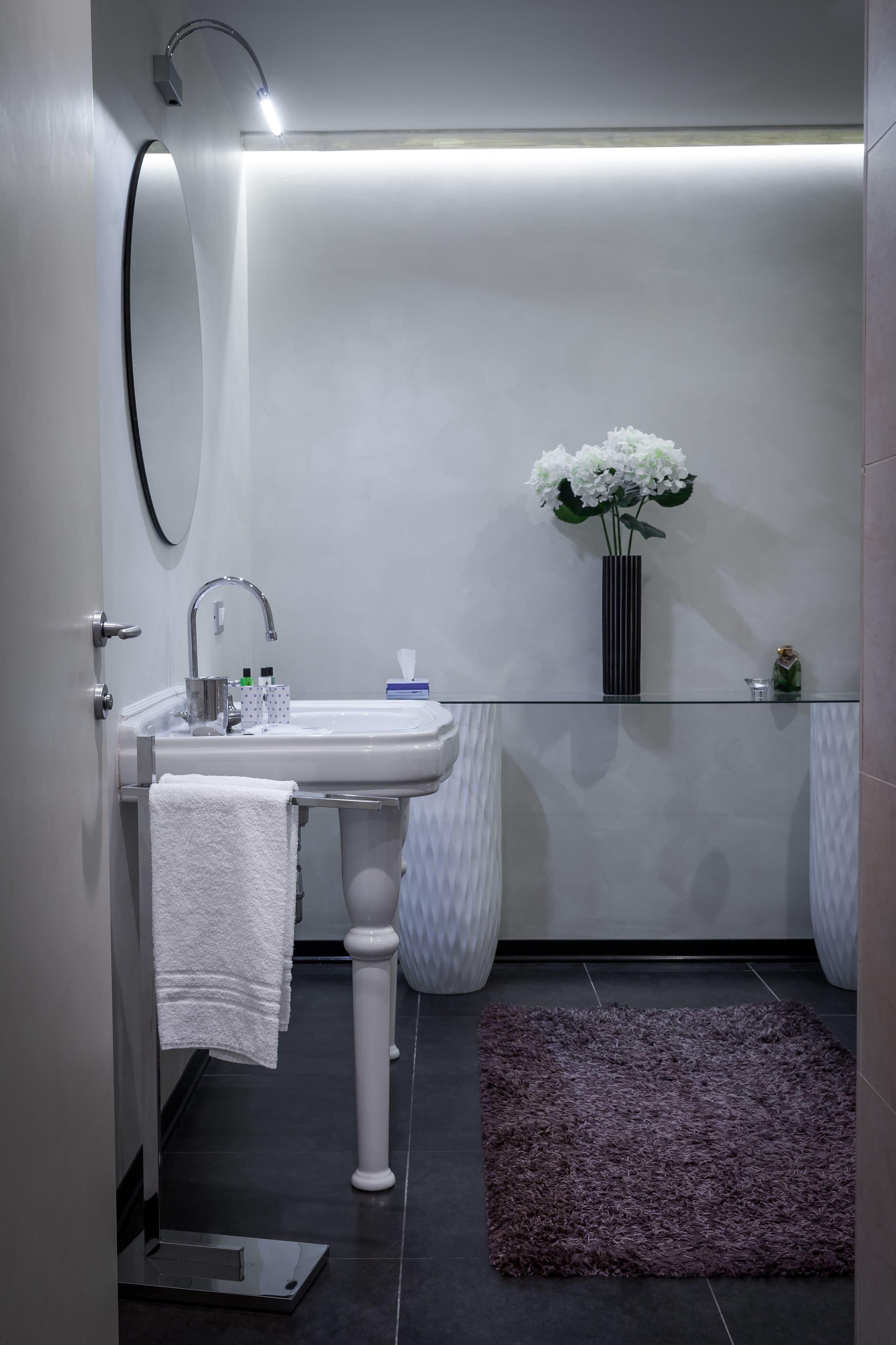 A modern bathroom with a white sink, a mirror, and a glass shower enclosure.