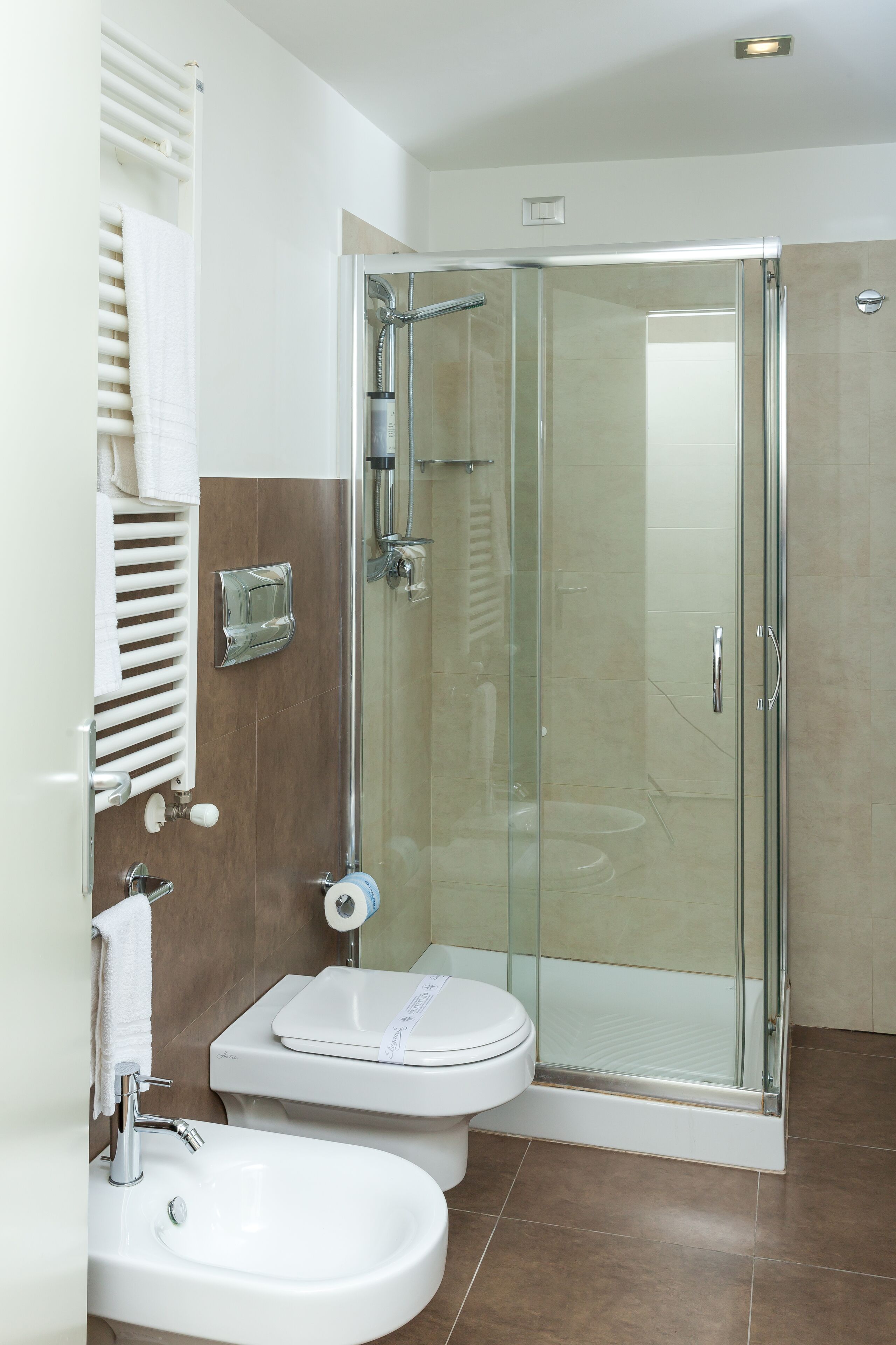 A modern bathroom with a glass-enclosed shower, a white sink, and a toilet.