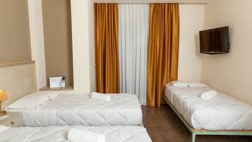 Ein Hotelzimmer mit zwei Betten, einem an der Wand montierten Fernseher und einem Fenster mit Vorhängen.