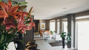 A modern hotel lobby with a seating area, a dining space, and large windows. - Modica Palace Hotel (Modica)