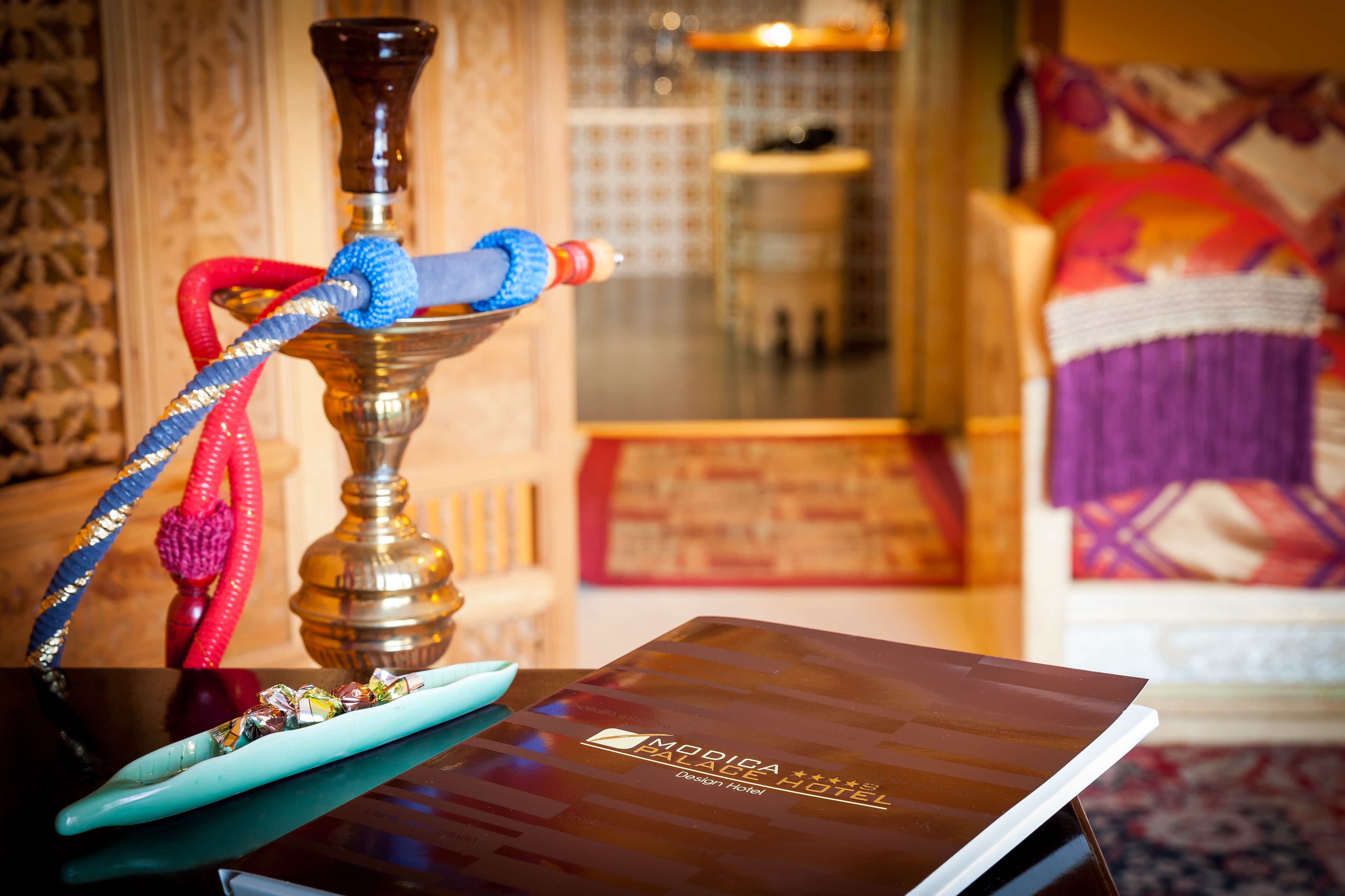 Un narguile sobre una mesa con un folleto del Hotel Medina Palace.