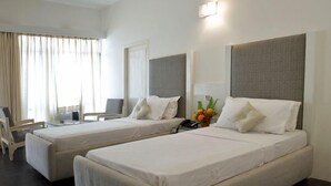 Une chambre d’hôtel avec deux lits, un bureau et une chaise.