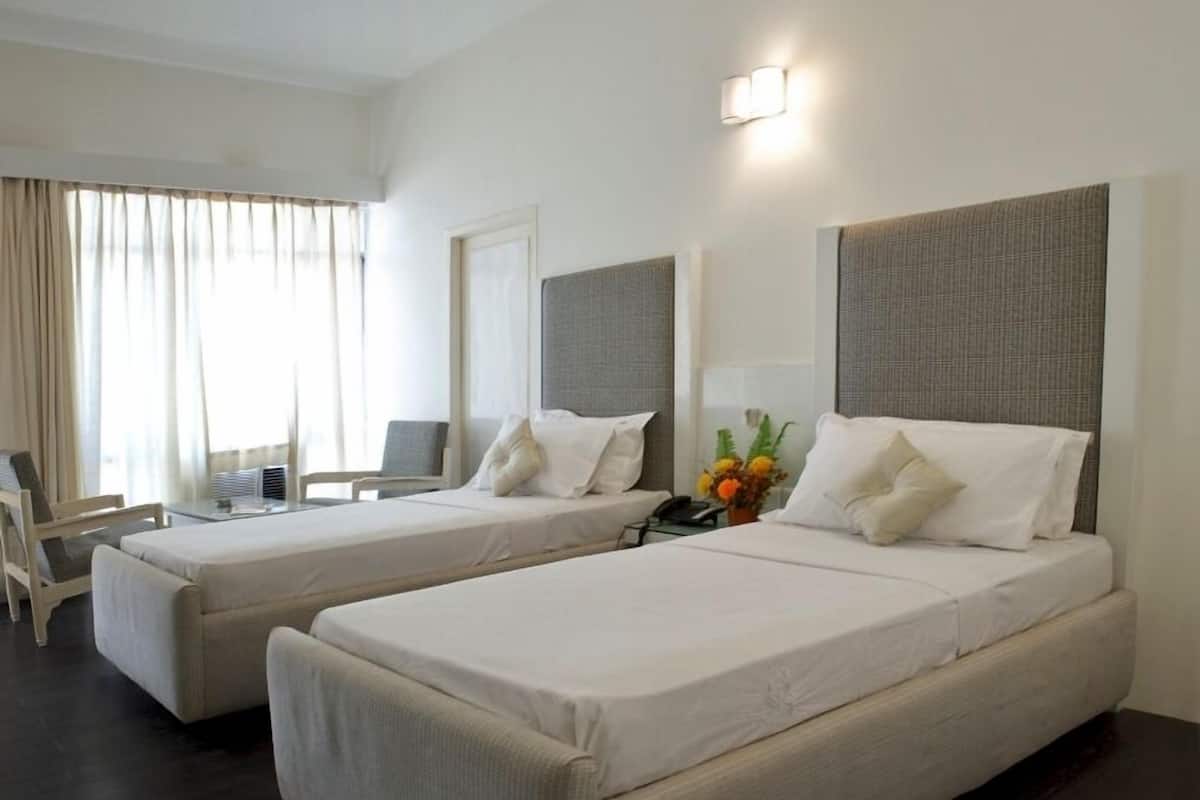 Habitació d'hotel amb dos llits, un escriptori i una cadira.