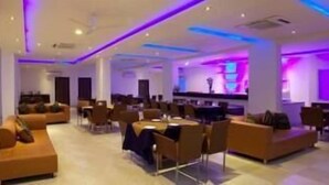 Un hall d’hôtel moderne, doté d’espaces aménagés avec des sièges, d’un comptoir d’accueil et d’un éclairage d’ambiance.
