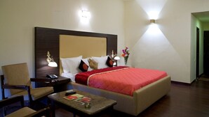 Une chambre d’hôtel avec un lit, une table de chevet, une chaise et une petite table avec une lampe.