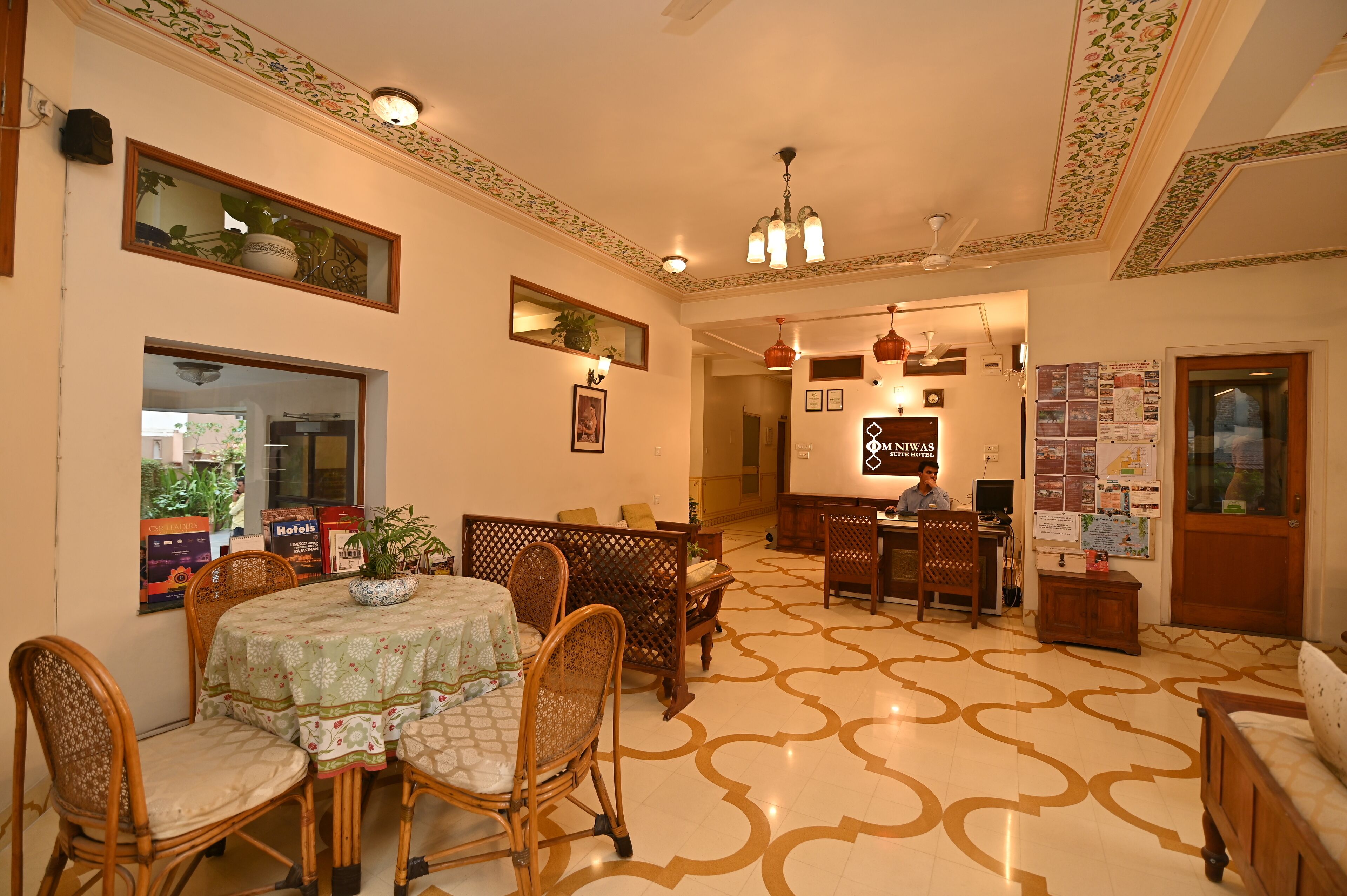 A hotel lobby with a dining area, a reception desk, and a seating area.