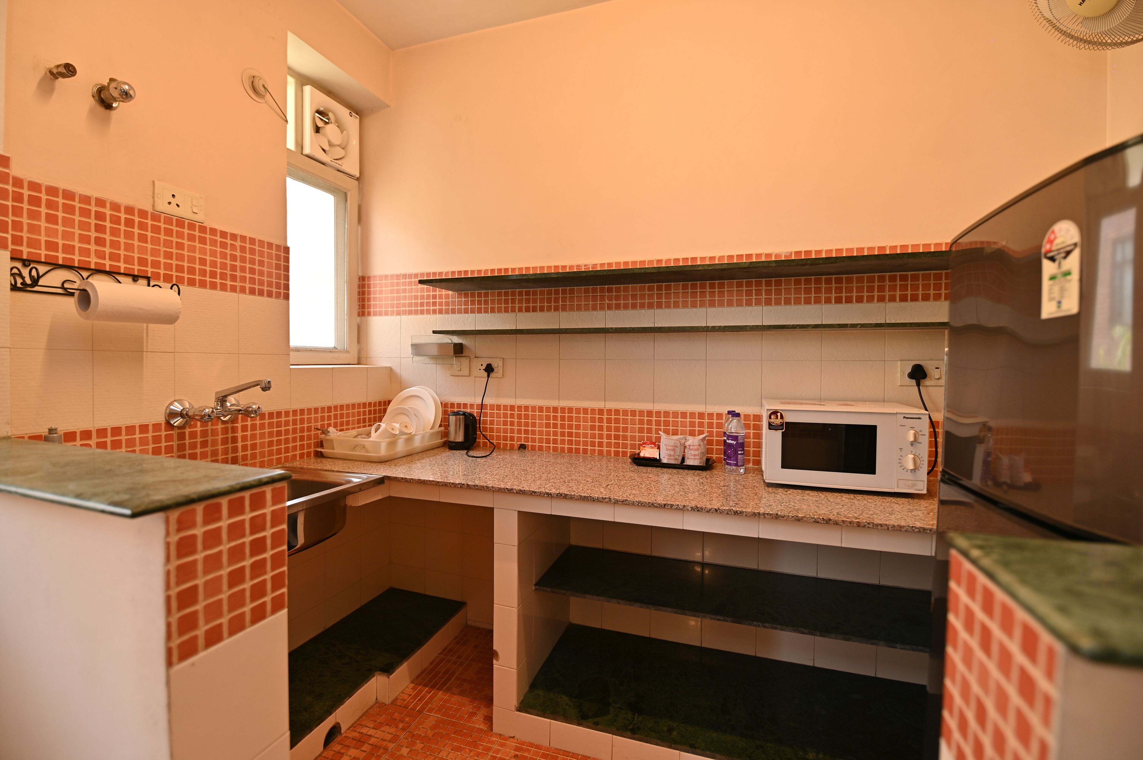 Cocina compacta con fregadero, microondas y ventana sobre la encimera.