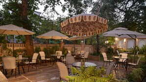 Eine Terrassengruppe mit Tischen und Stühlen, umgeben von Bäumen und Pflanzen.
