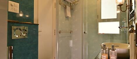 A modern bathroom with a freestanding bathtub, a glass shower enclosure, and a vanity with a mirror and light fixture.
