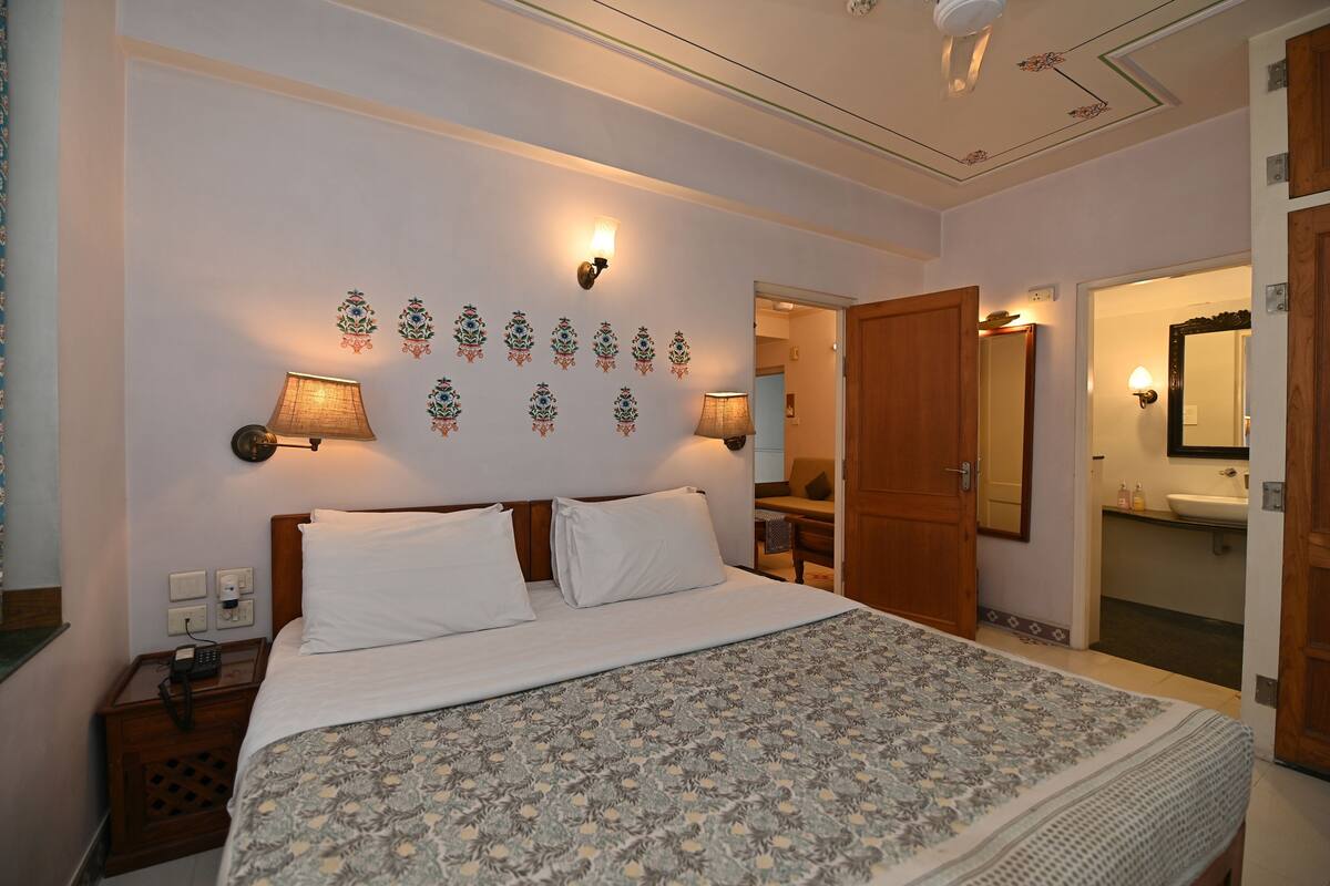 Une chambre d’hôtel avec un grand lit, deux lampes de chevet, un téléphone et un miroir.