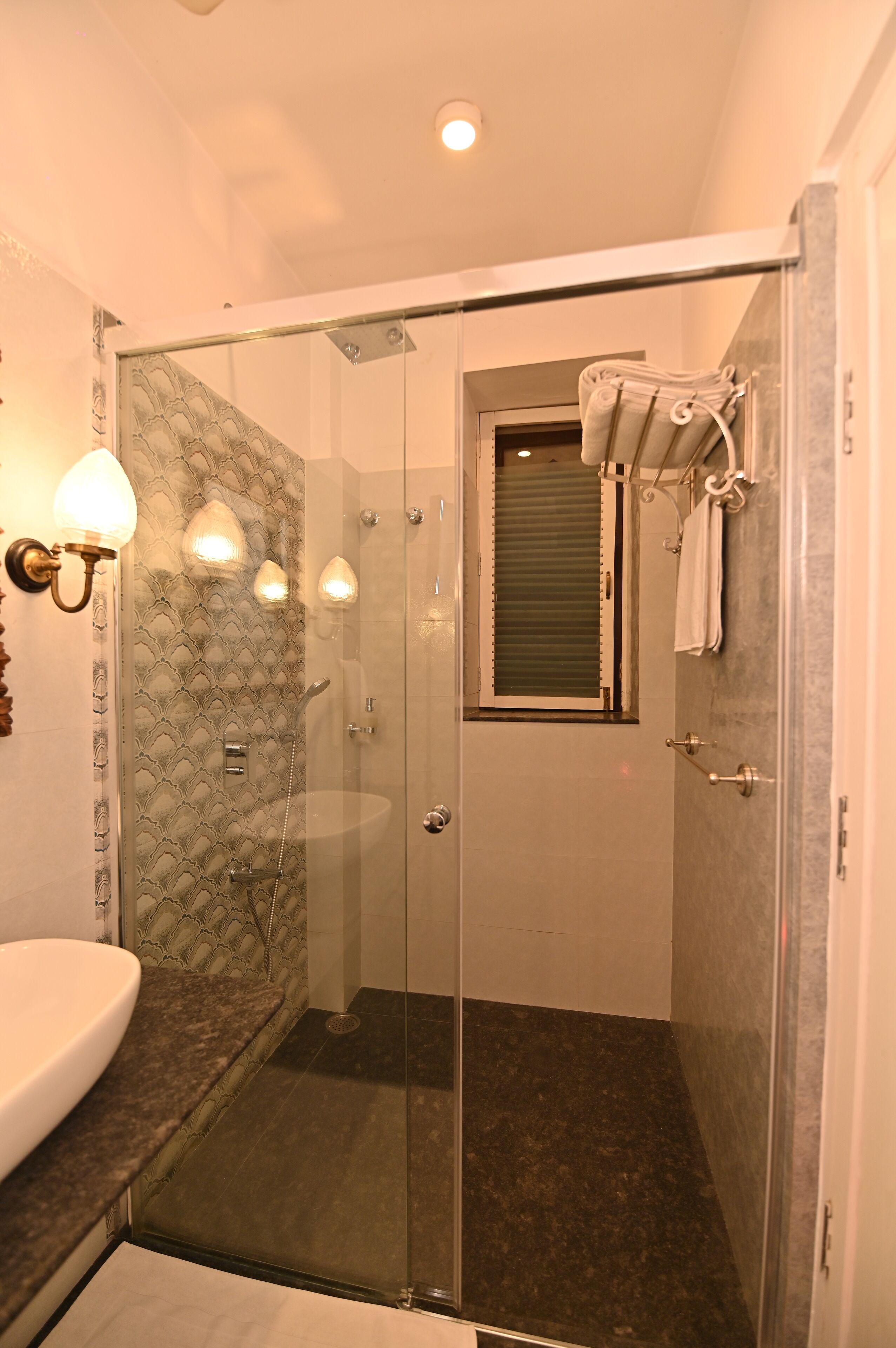 A modern bathroom with a glass-enclosed shower, a vanity with a marble countertop, and a wall-mounted towel rack.