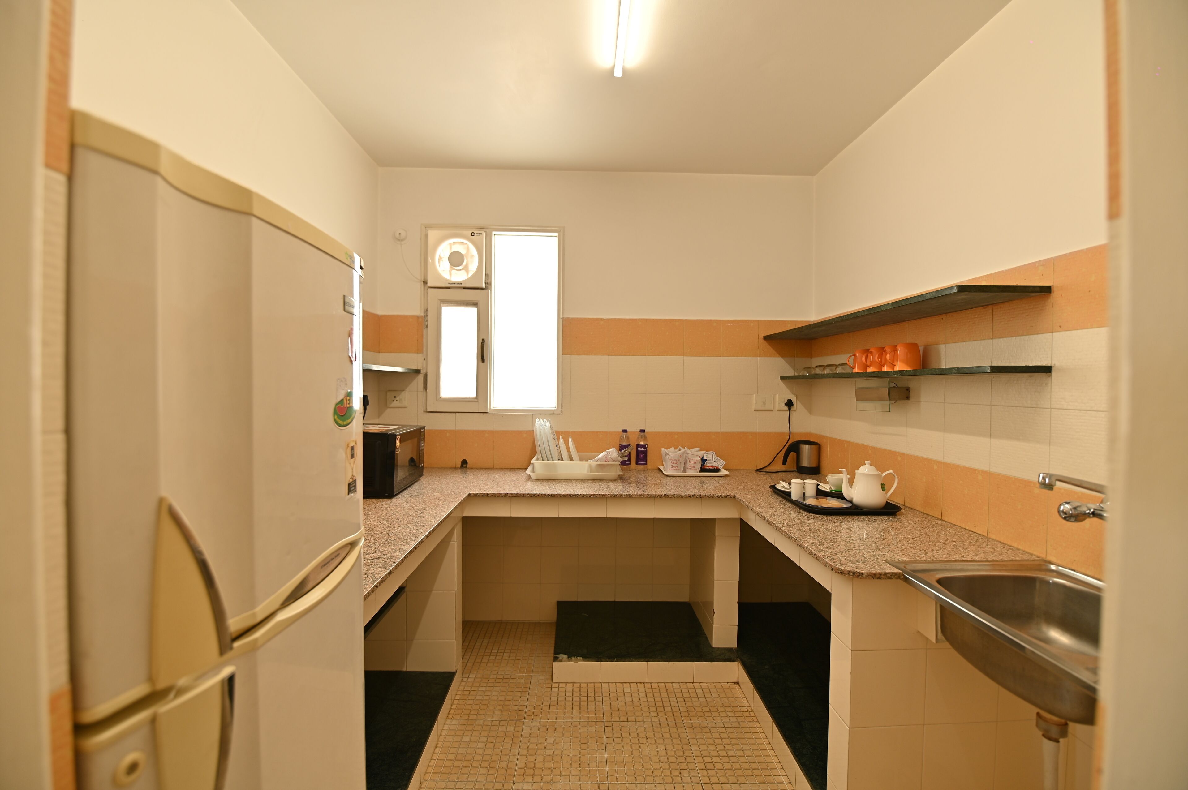Una cocina compacta con refrigerador, lavamanos y encimera con diversos utensilios de cocina.