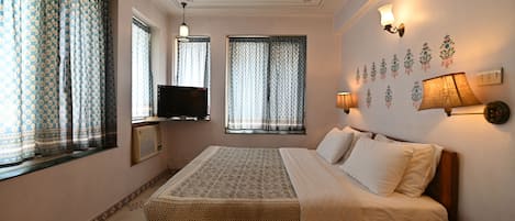 Un dormitorio ordenado con cama, lámparas de noche, televisor de pantalla plana y decoración en la pared.