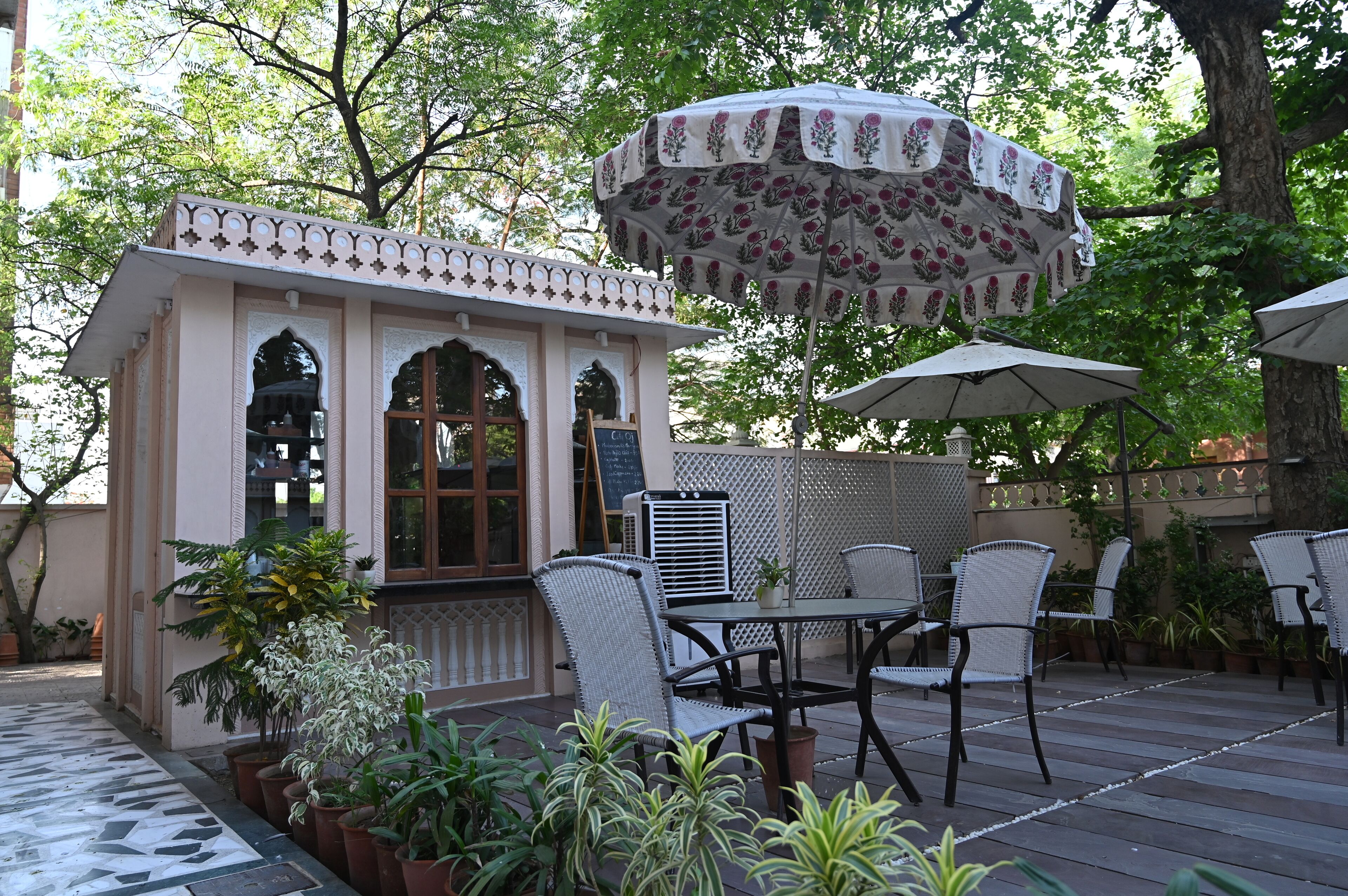 An outdoor patio with a small building, wicker chairs, and potted plants.
