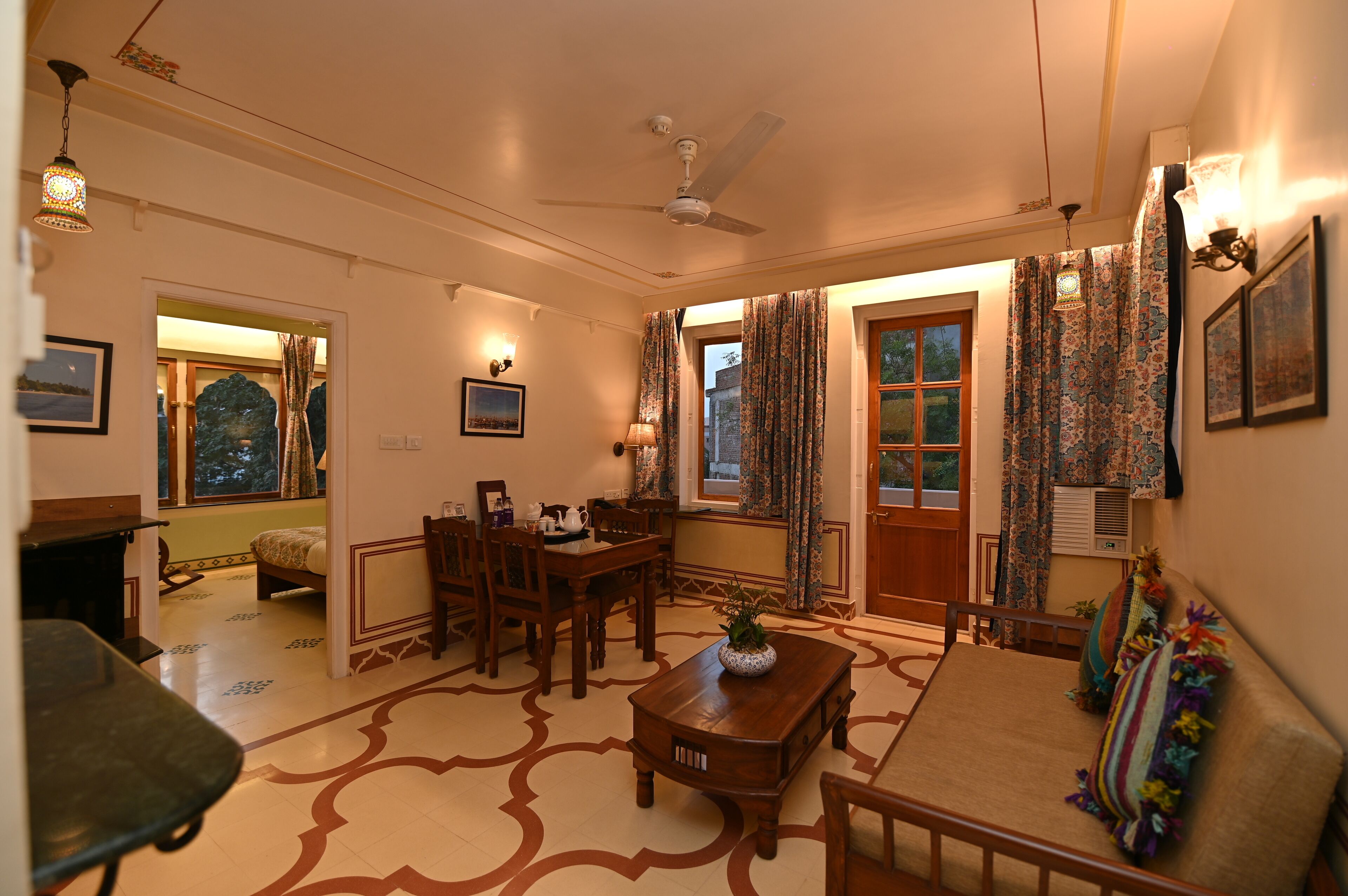 A cozy living room with a dining area, a ceiling fan, and a large window with curtains.