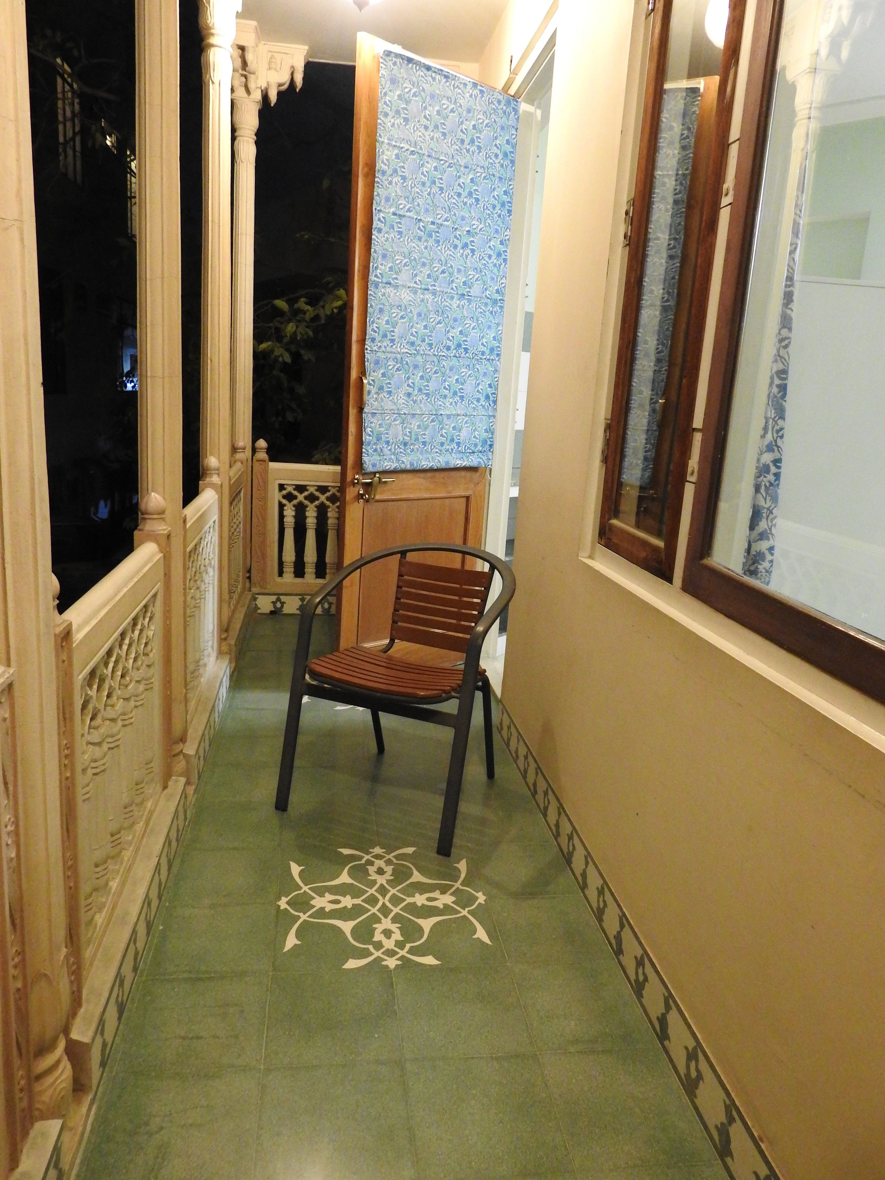 A narrow corridor with a chair, a door with a patterned curtain, and a decorative floor design.