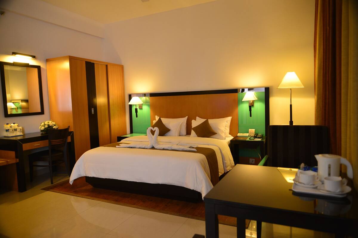A hotel room with a large bed, bedside tables, a desk, and a chair.