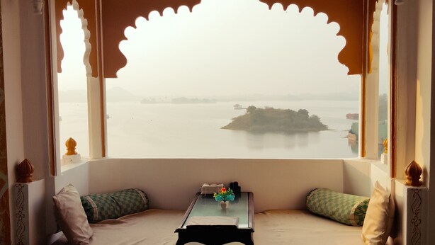 Habitación tradicional con sofá cama, una pequeña mesa y vista a un cuerpo de agua.