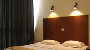 A hotel room with a wooden bed, two bedside lamps, and a dark curtain.