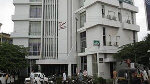A multi-story building with a modern architectural style, featuring balconies and air conditioning units.