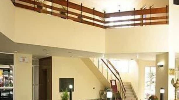 A spacious lobby with a red seating area, a staircase, and a reception desk.