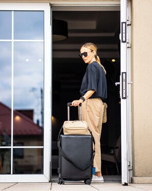A person with a suitcase and a handbag standing at a doorway. - Dosłońce Resort Wellness & Farm (Raclawice)