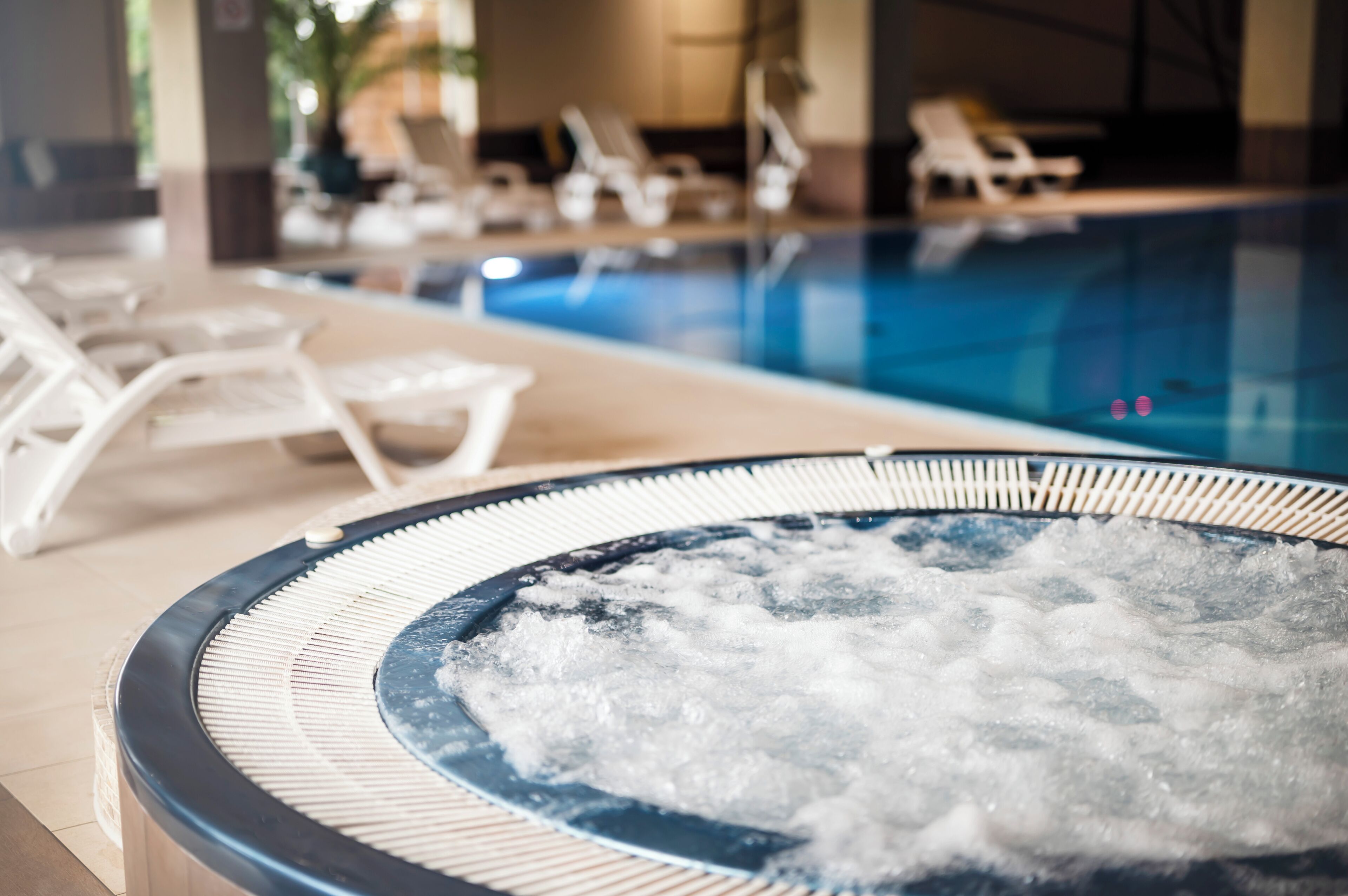 Un jacuzzi con hielo, sillas reclinables y una piscina al fondo.