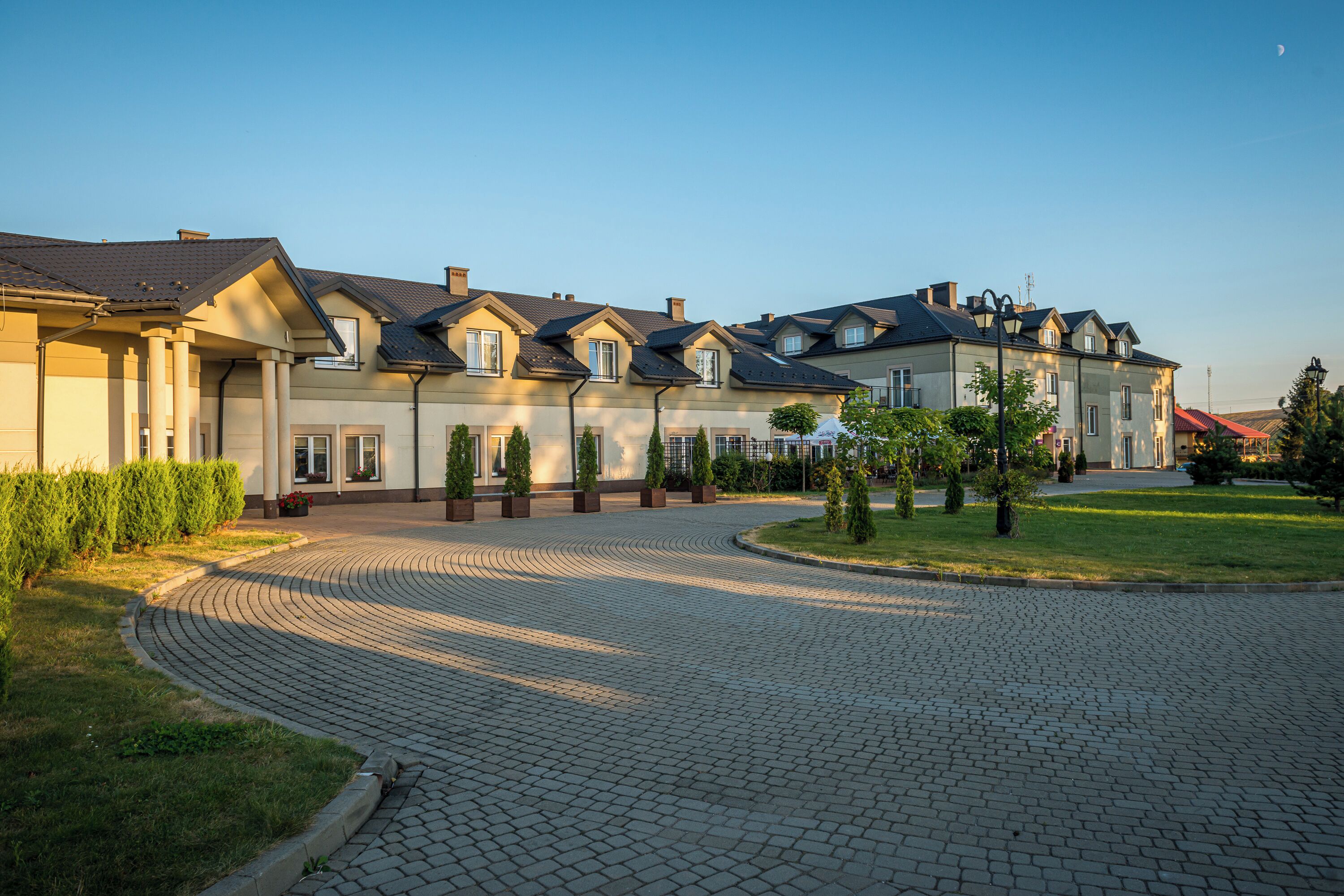 A residential building with a curved driveway, multiple windows, and a well-maintained lawn.