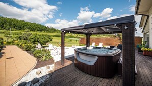 A hot tub under a pergola on a wooden deck with a view of a green landscape. - Dosłońce Resort Wellness & Farm (Raclawice)