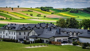 A large, multi-story building with a symmetrical facade, a covered outdoor area, and a well-maintained lawn. - Dosłońce Resort Wellness & Farm (Raclawice)