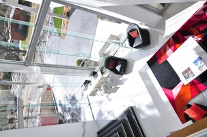 Un interior moderno con techo de cristal, asientos de diseño en tonos rojo y negro, y un mostrador de recepción blanco.