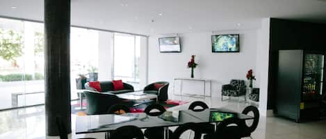 A modern dining area with a glass table and black chairs, a large pillar, and a view of the outdoors.