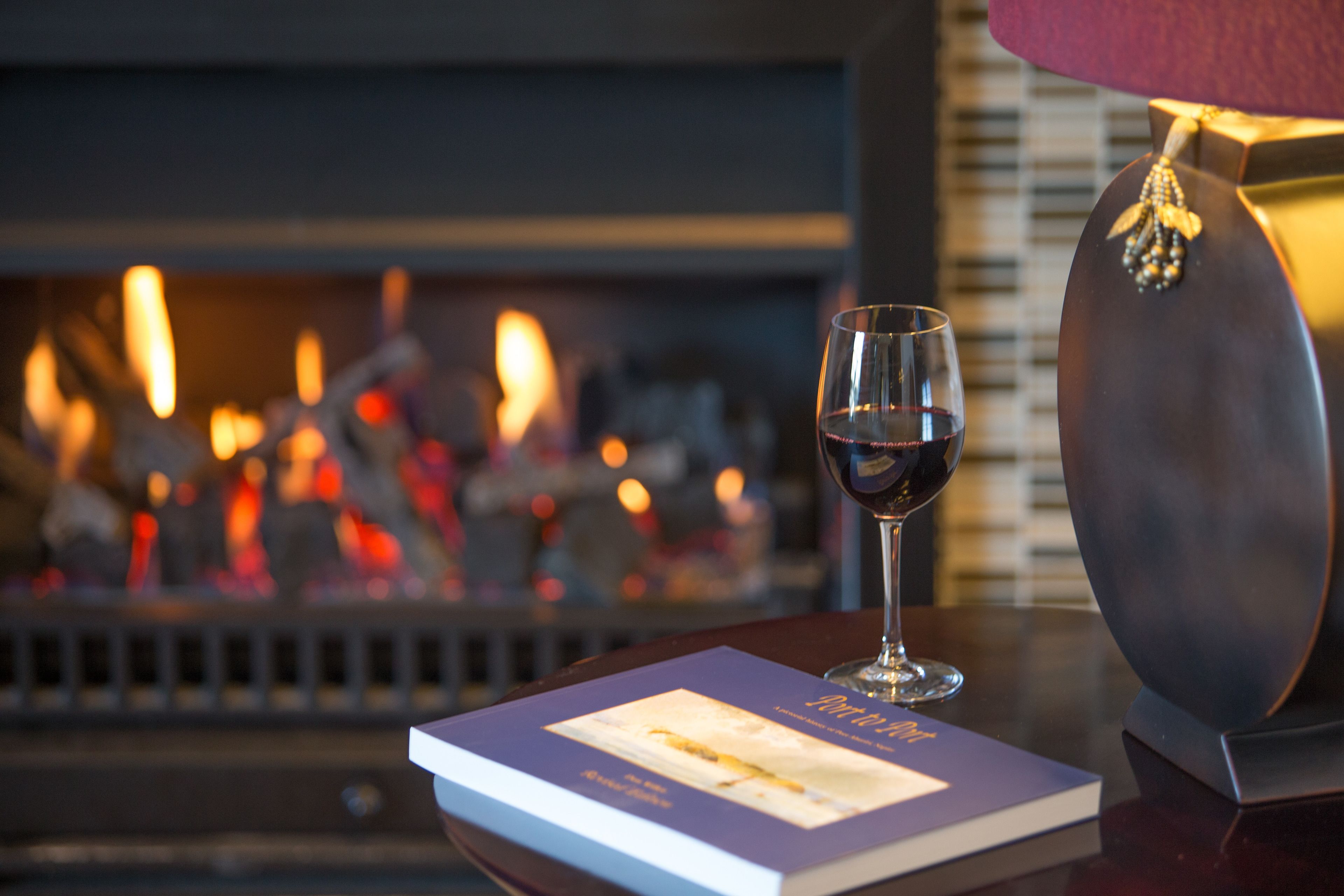 Una copa de vino tinto sobre una mesa con un libro y un objeto decorativo.