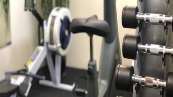A gym with exercise equipment including a stationary bike, a treadmill, and a rack of dumbbells.