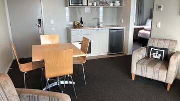 Habitació d'hotel compacta amb cuineta, zona de dinar amb taula i cadires, i zona de seients amb sofà i butaca.