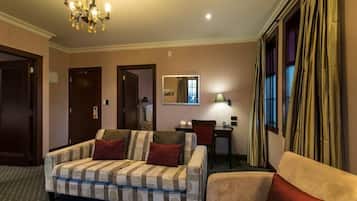 A hotel room with a checkered sofa, a smaller sofa, a dining table, and a mirror.