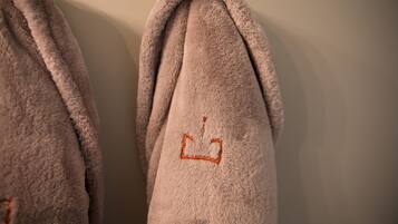 A close-up of a plush, light brown towel with a simple embroidered design on the folded end.
