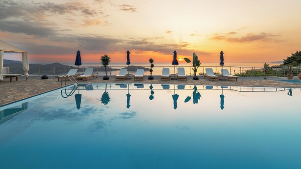 A poolside area with lounge chairs and umbrellas, reflecting the sunset. - Adrakos Apartments - Adults Only (Agios Nikolaos)