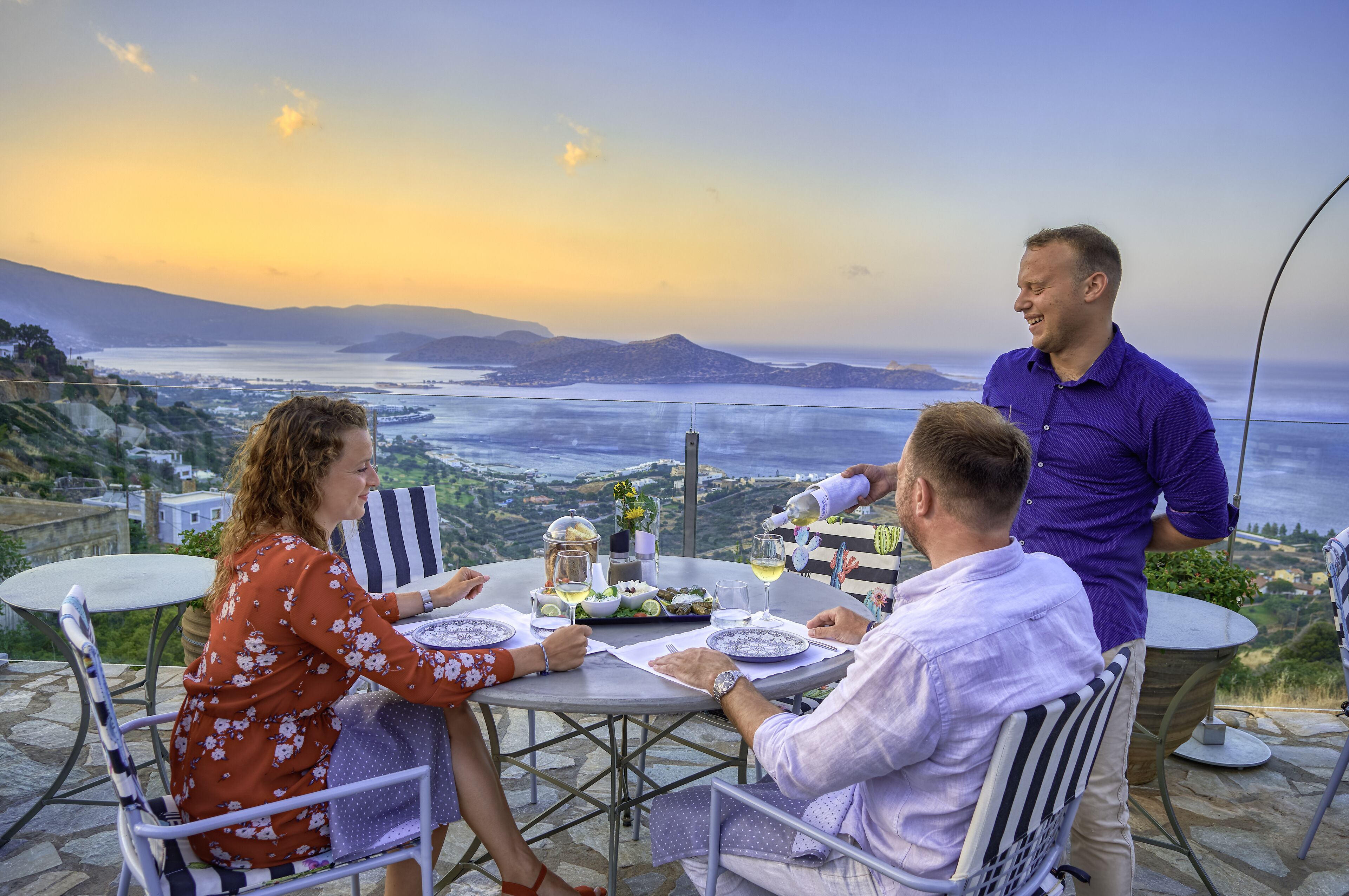 A table set outdoors with a scenic view of the ocean and hills.