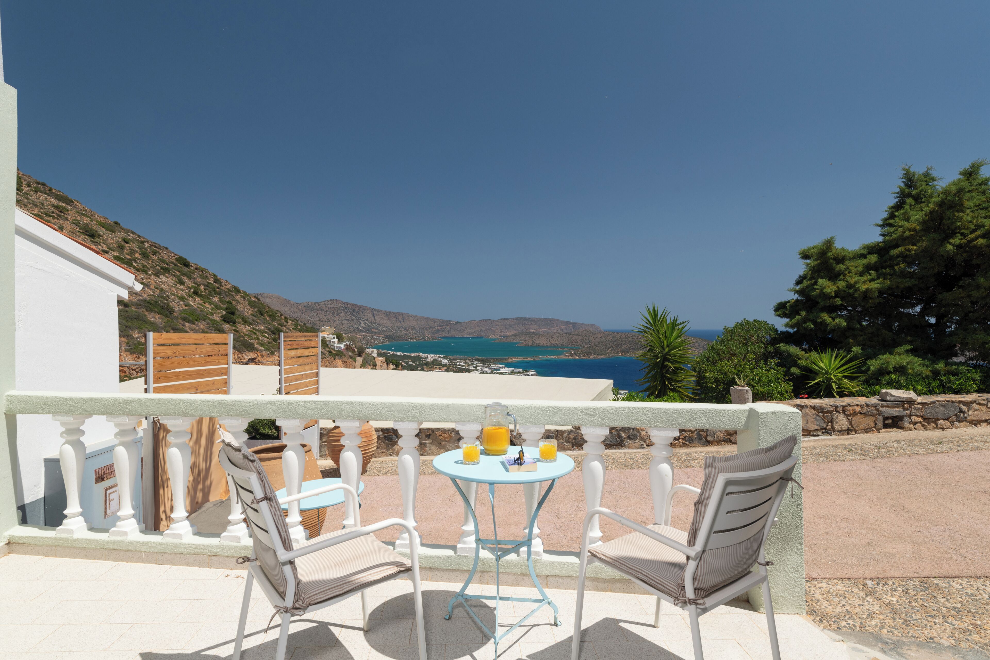 A balcony with a table and chairs, overlooking a scenic view of a coastal landscape.