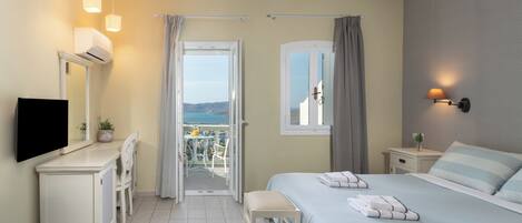 A hotel room with a bed, a desk, a chair, a TV, a window, and a balcony with a view.