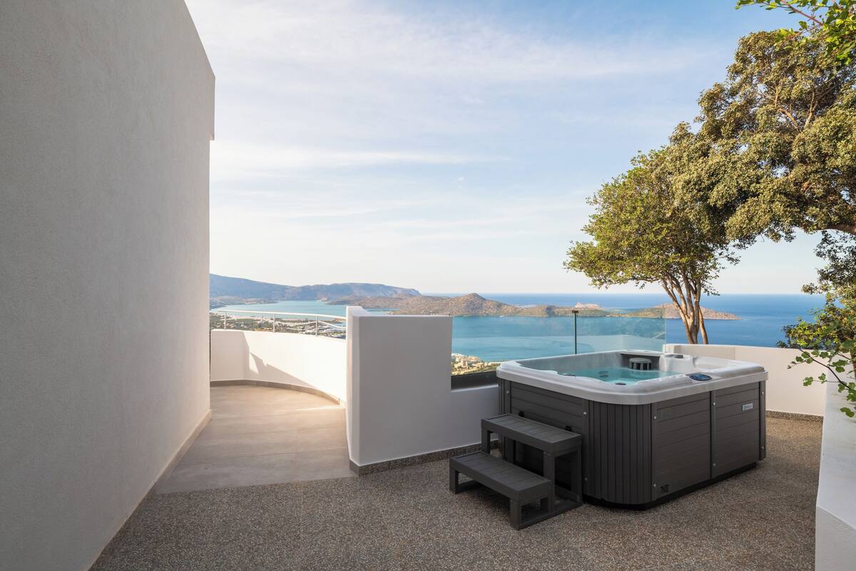 A hot tub on a balcony with a view of the sea and mountains.